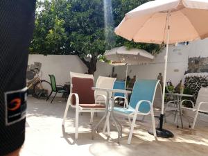 a group of chairs and tables with an umbrella at Marina's Rooms in Larnaca