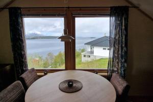 a table and chairs in a room with a large window at Central apartment with a view! in Harstad
