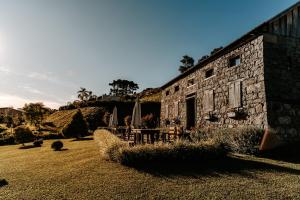a stone building with chairs and umbrellas in a yard at Pousada Cantelli in Bento Gonçalves