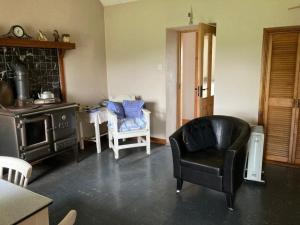 a living room with a black chair and a stove at Flaherty Cottage, Ballyconneely in Ballyconneely