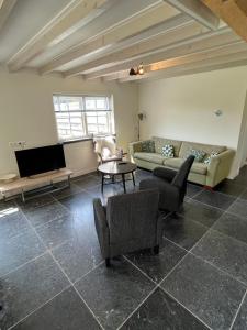 una sala de estar con un sofá y una mesa en Hèt Koetshuis, en Oostkapelle