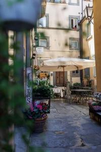 een steegje met een paraplu en tafels en stoelen bij La Finestrella in Cortona