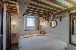 Un dormitorio con una cama blanca en una habitación con techos de madera. en La Finestrella, en Cortona