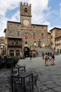 un grand bâtiment avec une tour d'horloge dans une cour dans l'établissement La Finestrella, à Cortone