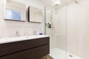 La salle de bains est pourvue d'un lavabo et d'une douche. dans l'établissement SERRENDY Sea view & terrace heart of Cannes, à Cannes