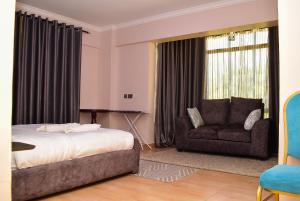 a bedroom with a bed and a couch and a chair at RAVIC HOMES NAKURU in Nakuru