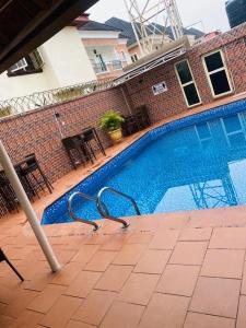 a swimming pool with chairs and tables next to a building at Presken Hotel @Villa in Ikeja