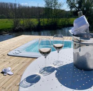 zwei Gläser Wein auf einem Tisch neben einem Pool in der Unterkunft Moulin de Fourges in Fourges