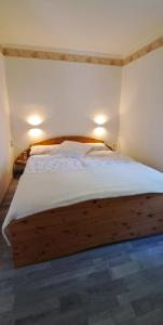 a bedroom with a wooden bed with white sheets at Tornower Waldhäusl, perfekt gelegen 60 km vor Berlin, auf der Schwelle zum Spreewald und nahe Tropical Islands 