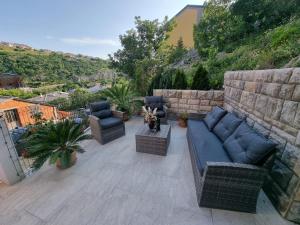 a patio with couches and chairs and a stone wall at Apartment Niko in Senj