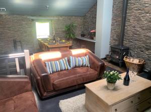 sala de estar con sofá de cuero y estufa de leña en La Maison Ardoise, en Herbeumont