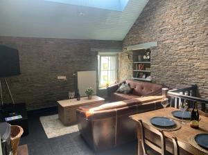 a living room with a leather couch and a brick wall at La Maison Ardoise in Herbeumont