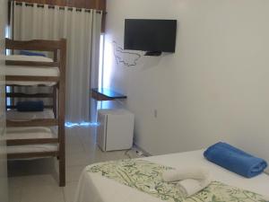 um quarto com uma cama e uma televisão na parede em Hope Pousada em Arraial do Cabo