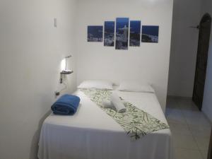 uma cama com uma colcha branca e duas almofadas em Hope Pousada em Arraial do Cabo