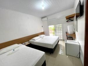 una camera con due letti e una tv di Nav Park Hotel a Naviraí