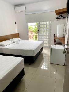 a hotel room with two beds and a balcony at Nav Park Hotel in Naviraí