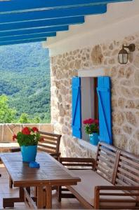 a patio with a wooden table and benches and blue shutters at Etno house HAPPY VILLAGE in Cetinje
