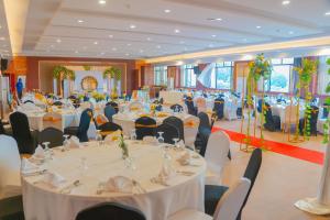 un salón de banquetes con mesas y sillas blancas en M Hotel Kigali en Kigali