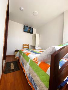 1 dormitorio con 1 cama y TV en la pared en Hostal La Terraza en Quito