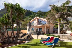 una casa con palmeras y tumbonas en Porto Moniz Villa en Porto Moniz