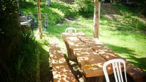un banco de madera con dos sillas blancas sentadas en el césped en Cascina Marasca Appartamento Viola en Martina Olba
