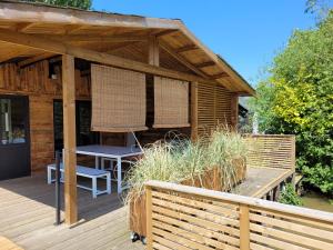 una terrazza in legno con tavolo e sedia di Rustig gelegen chalet Solvo met terras aan het water a Geel