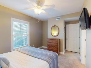 een slaapkamer met een bed en een plafondventilator bij Silver Shores Unit 8 in Tybee Island