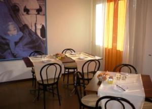 un comedor con mesas, sillas y una pintura en Hotel Sport, en Portogruaro