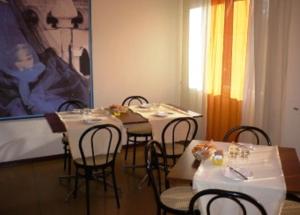 una sala da pranzo con tavoli, sedie e un dipinto di Hotel Sport a Portogruaro