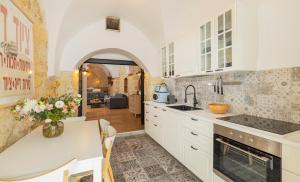 a kitchen with white cabinets and a table with a vase of flowers at Sapir Boutique Apartments in Beer Sheva