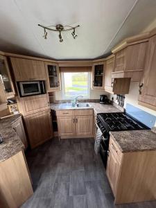 a kitchen with wooden cabinets and a stove top oven at Heron View Holiday Home in Balminnoch