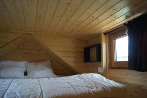 a bed in a wooden room with a window at Spa & Bain Nordique - Tiny house à la campagne in La Boissière