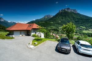 zwei Autos auf einem Parkplatz mit Bergen im Hintergrund geparkt in der Unterkunft Coquet T2. Exceptionnel entre lac et montagnes in Menthon-Saint-Bernard