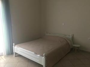 ein weißes Bett in einem weißen Zimmer mit Fenster in der Unterkunft Theros Apartments in Mirina