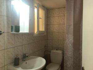 ein Bad mit einem Waschbecken, einem WC und einem Fenster in der Unterkunft Theros Apartments in Mirina
