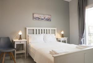 a white bedroom with a white bed and a chair at Raptis Guest House in Tsilivi