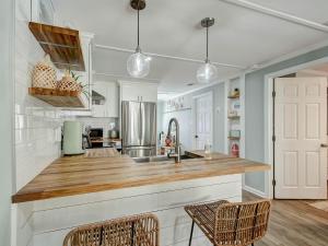 a kitchen with a counter with chairs and a refrigerator at Walking on Sunshine in Tybee Island
