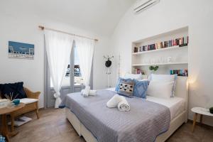 a white bedroom with a bed with towels on it at Blue Canvas in Perissa