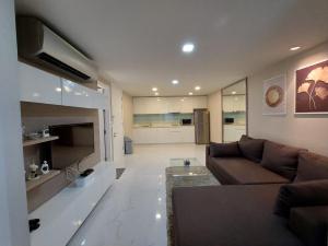 Condominium Sukhumvit Soi 5 - BTS Nana- Room Size 47m2 في Makkasan: غرفة معيشة مع أريكة بنية ومطبخ