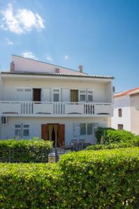 una gran casa blanca con una valla delante en Apartmani Ina Pag, en Pag