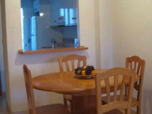 a wooden table with chairs and a bowl of fruit on it at Beach Holiday home with wifi and air con in Torre de la Horadada