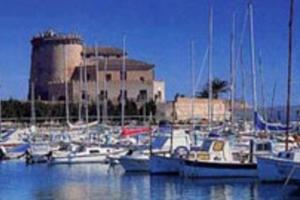 a bunch of boats in a marina with a castle in the background at Beach Holiday home with wifi and air con in Torre de la Horadada