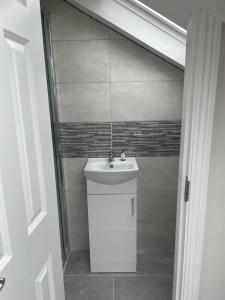 La salle de bains est pourvue d'un lavabo blanc et d'une douche. dans l'établissement New House, Private Rooms in a Peaceful Neighborhood, à Dublin