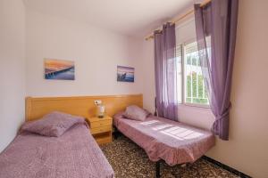 - une chambre avec 2 lits et une fenêtre avec des rideaux violets dans l'établissement Can Quetu, à Vinaròs 14 autres photos