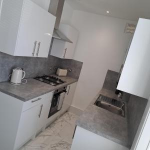 a small kitchen with white cabinets and a sink at Maze 21one Apartment in Ayr