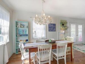 a dining room with a table and white chairs at Barefoot Children in Tybee Island