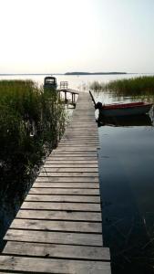 muelle de madera con un barco en el agua en Domek nad brzegiem jeziora Śniardwy z własnym pomostem, zejściem do wody i przecudnym widokiem na jezioro, en Zdory