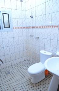 y baño con aseo blanco y lavamanos. en Appart meuble Jouvence chez Chantal & Francis, en Yaoundé