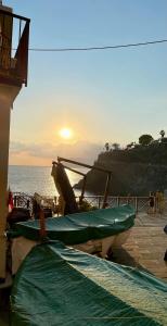 a boat sitting on the beach with the sun in the background at Salty Dreams Manarola in Manarola