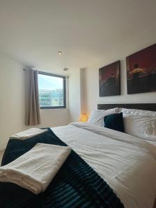 a bedroom with a large white bed with a window at Super Modern 3-Bedroom Apartment in London